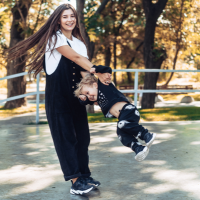 A mother safely spinning her child around in the park