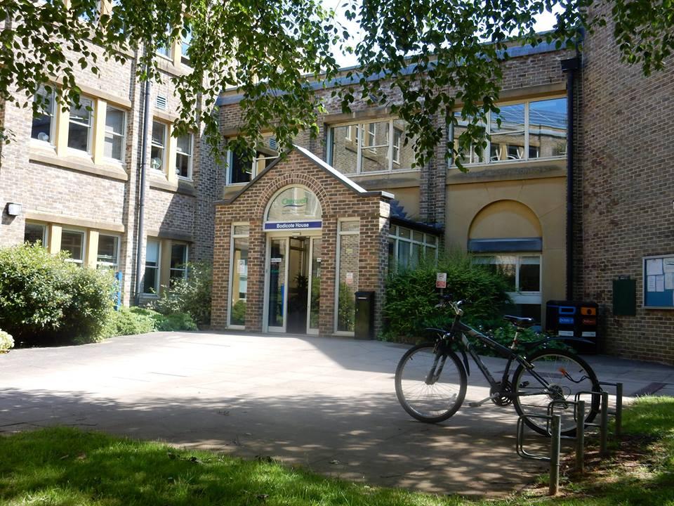 A bicycle it locked up outside Bodicote House on a sunny day