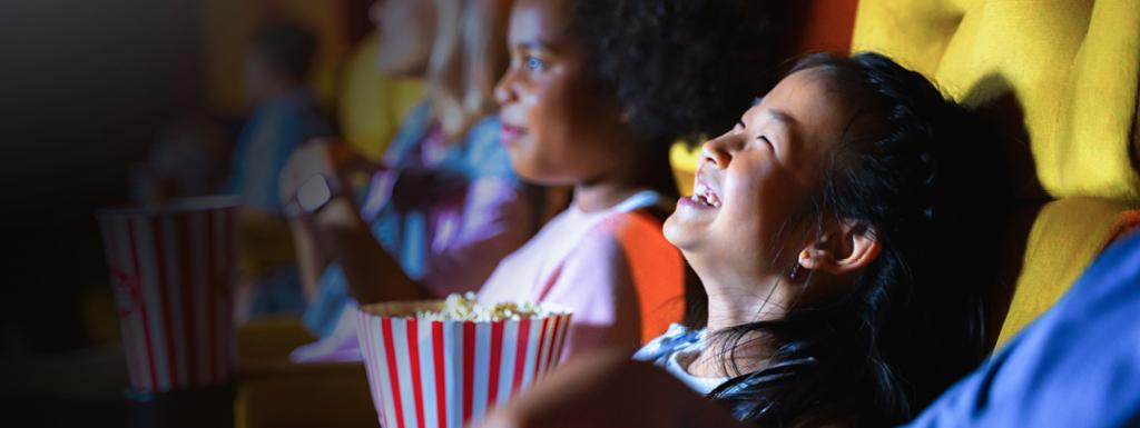 Kids watching film in a cinema whilst eating popcorn