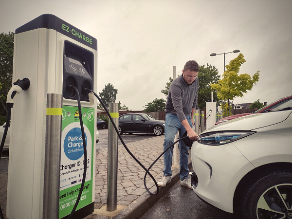 A man is hooking up his electric vehicle to the chargers at Curtis Place car park in Kidlington