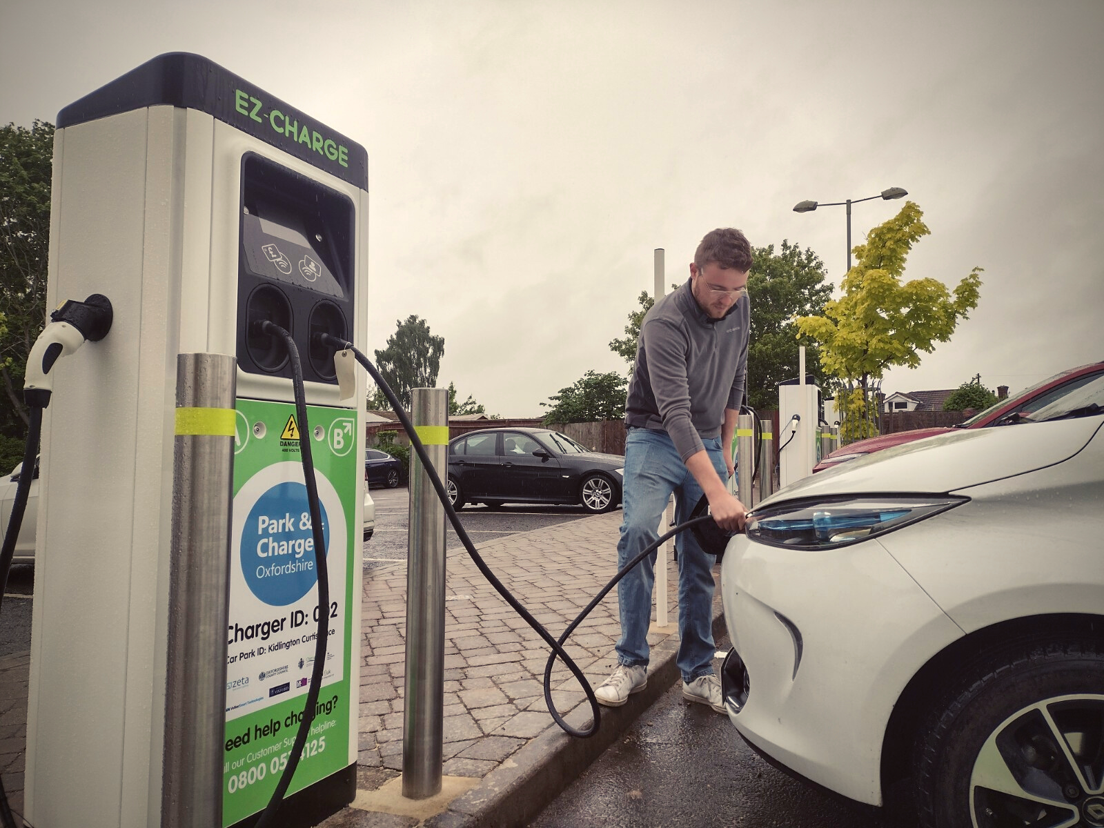 A young man is connecting his car to the charger at the car park in Kidlington