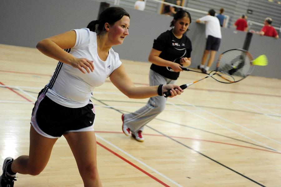 two ladies are playing badminton in a leisure centre