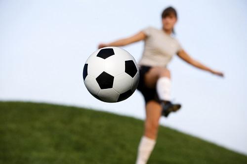 a woman kicking a football