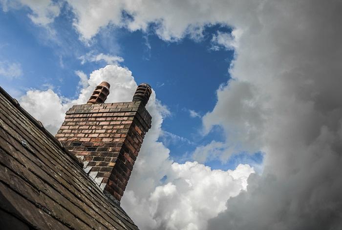 A rooftop and chimney set against a cloudy sky