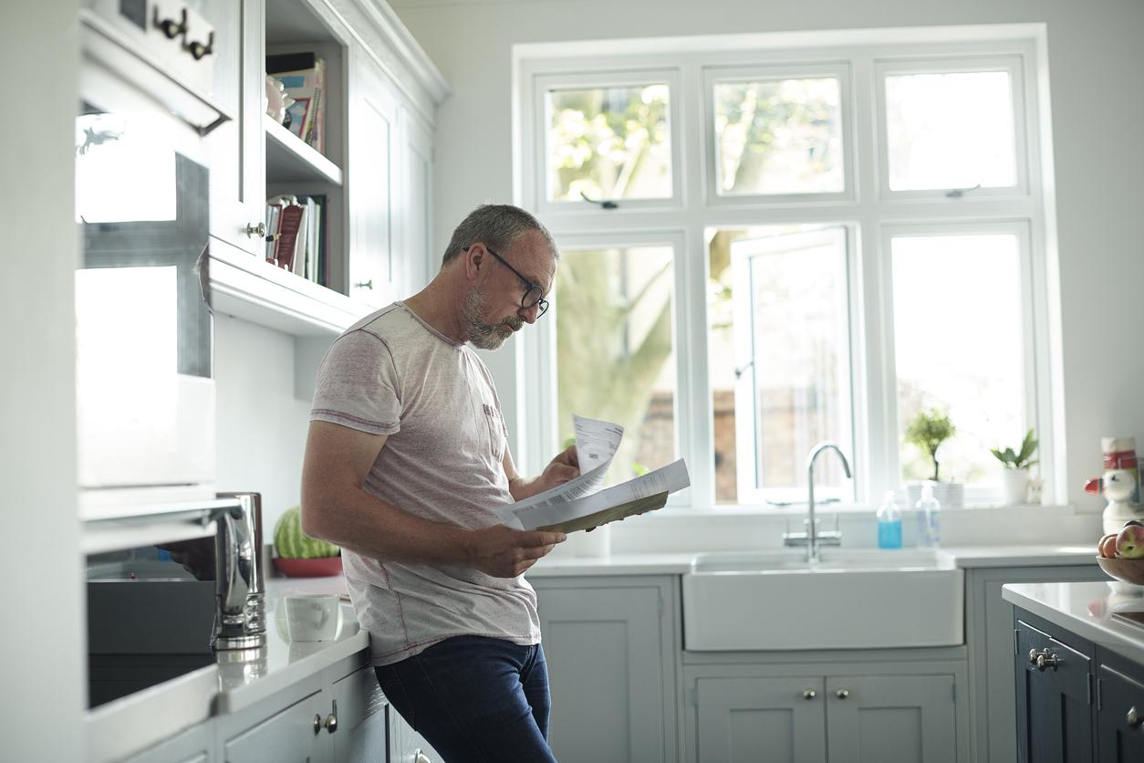 A man is reviewing his council tax bill in the kitchen