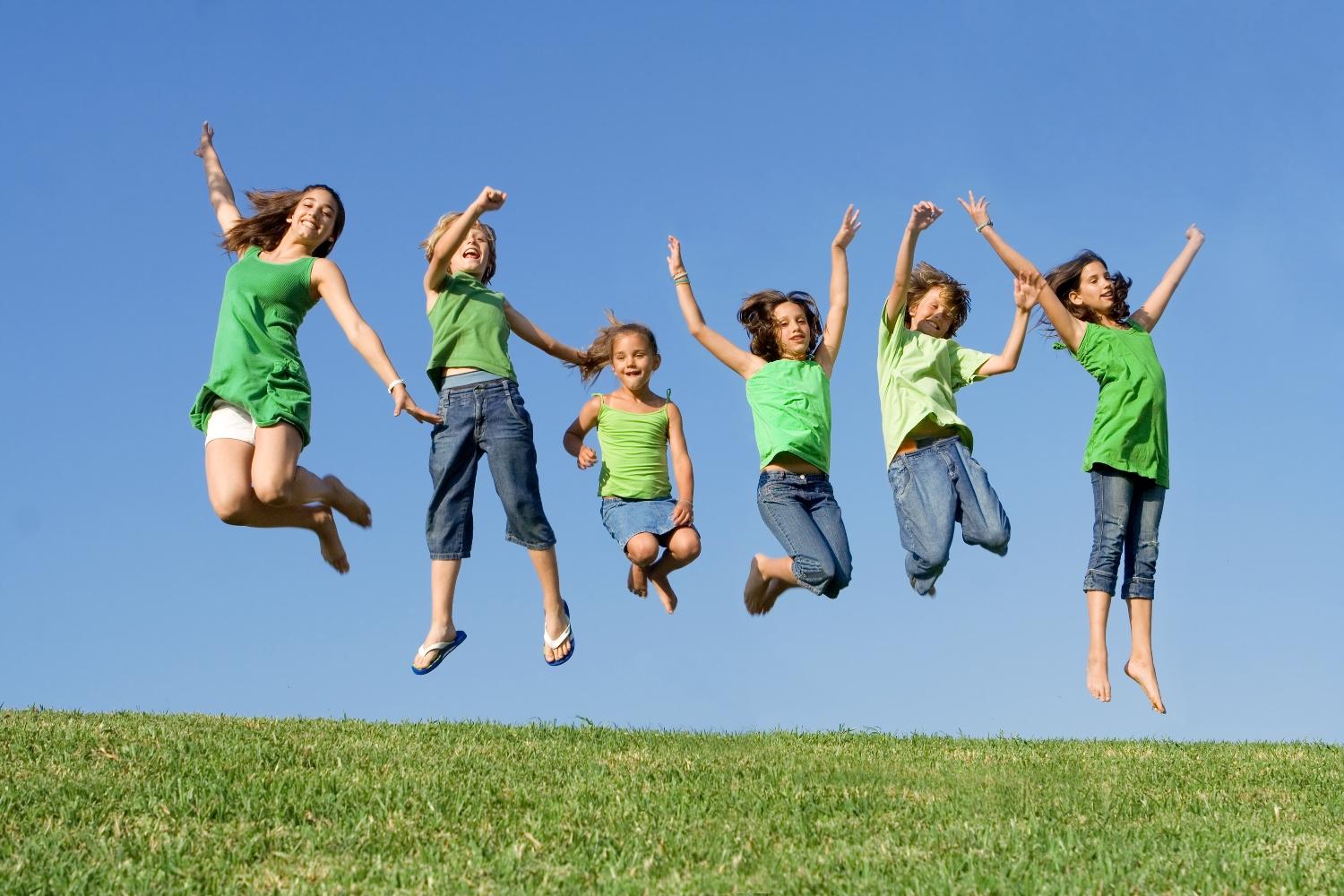 A group of kids are jumping for joy on a sunny day