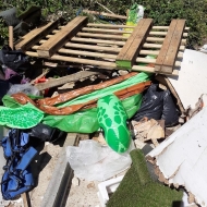 A big pile of illegal waste, including a wooden pallet and an inflatable turtle.